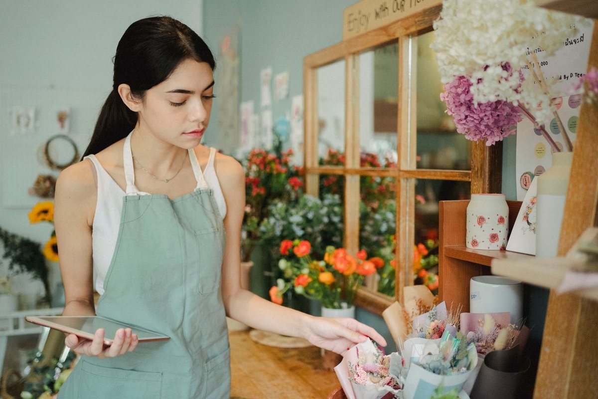 Flower shop owner using a smartphone in her store