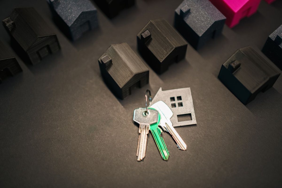 House keys resting beside a miniature home