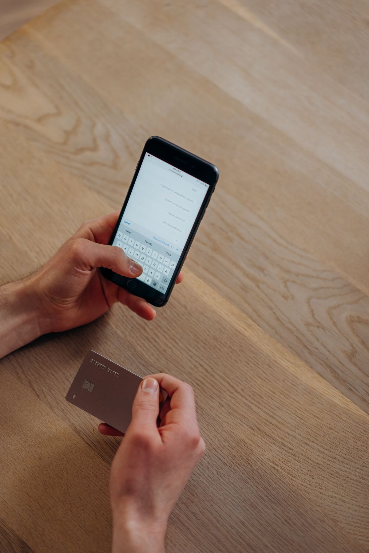 Hands using a smartphone beside a payment card
