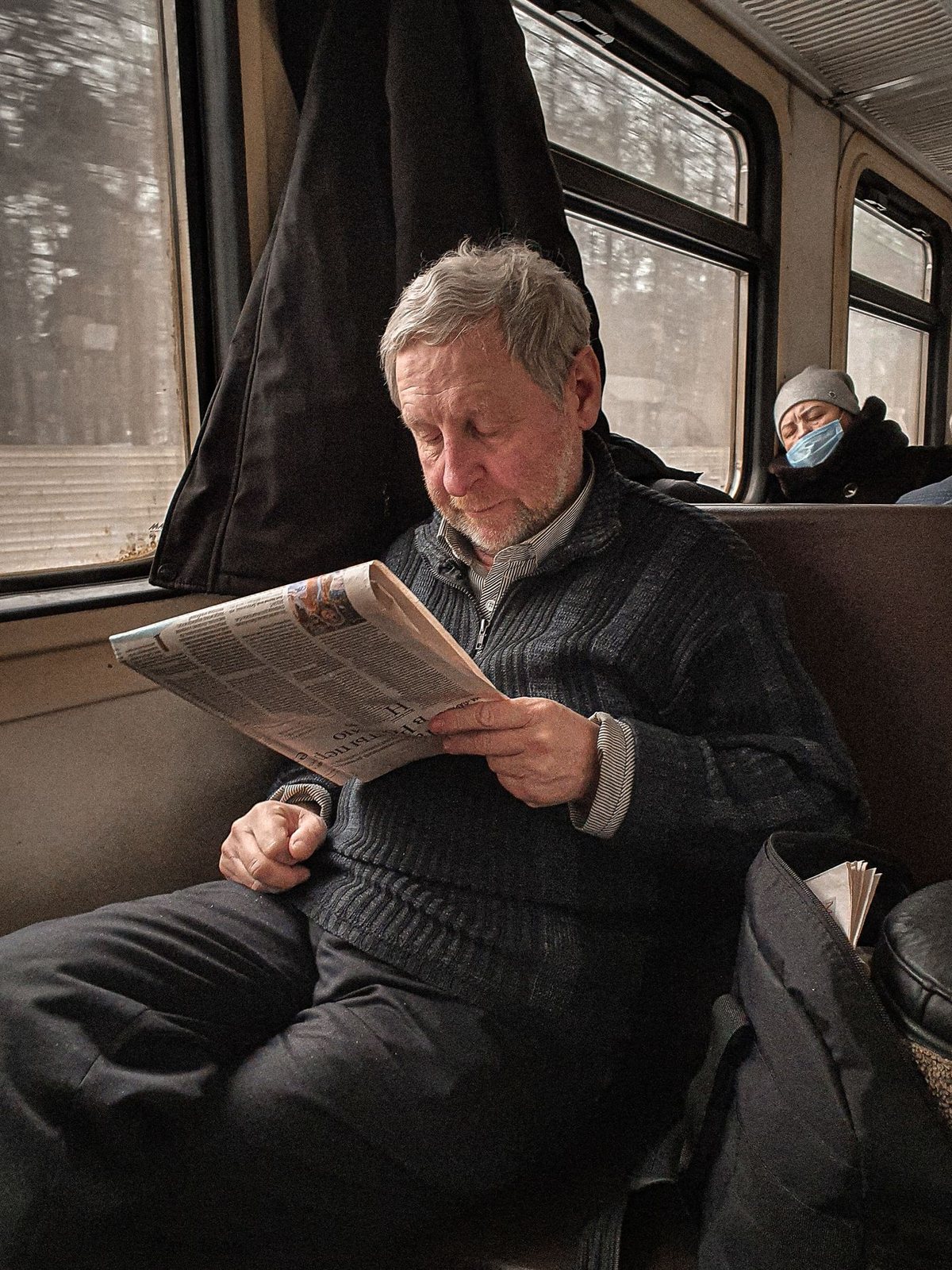 A commuter reading a newspaper on a train