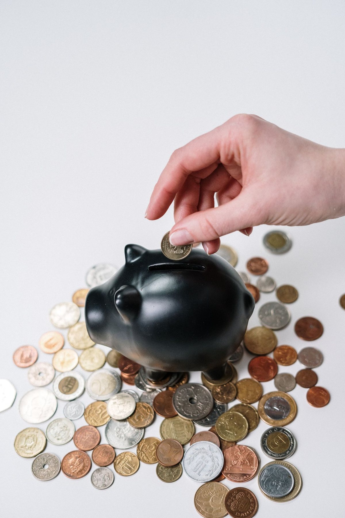 Coins surrounding a black piggy bank